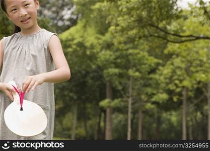 Girl holding a racket and a shuttlecock in a garden