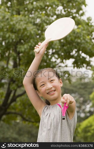 Girl holding a racket and a shuttlecock in a garden