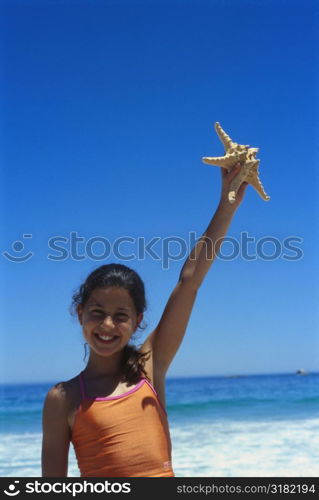Girl holding a starfish in her hand on the beach