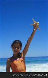 Girl holding a starfish in her hand on the beach