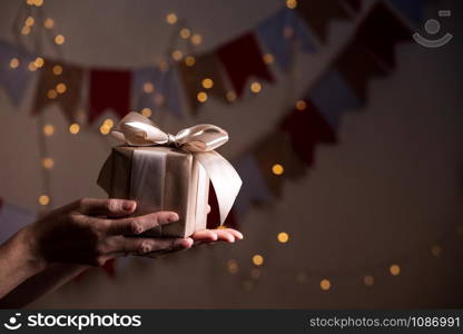 girl holding beautiful gift for the day valentines day. box and bow and bokeh in the background