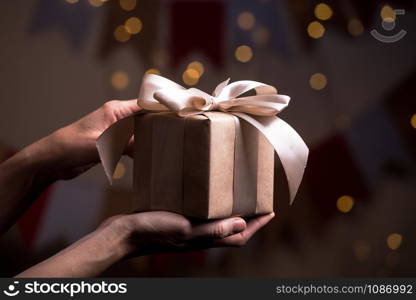 girl holding beautiful gift for the day valentines day. box and bow and bokeh in the background