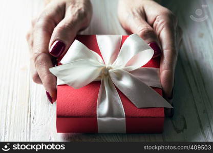 girl holding beautiful gift for the day valentines day. red box and white bow