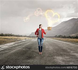 Girl holding box in hand. Happy young woman in red jacket opening gift box