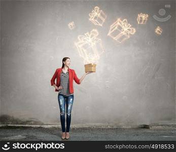 Girl holding box in hand. Happy young woman in red jacket opening gift box