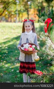 Girl holding Christmas decoration in a basket in her hands. Merry Christmas and happy holidays.. Girl holding Christmas decoration in a basket in her hands.