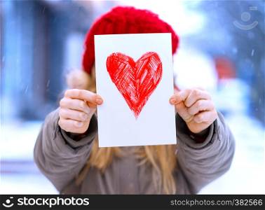 girl holding drawing with a heart on the valentines day