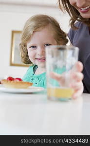 Girl holding glass of juice on table