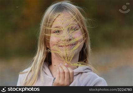 Girl holding leaf in front of her face
