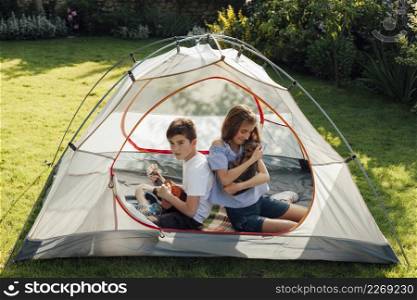 girl holding little dog sitting with her brother tent camp park