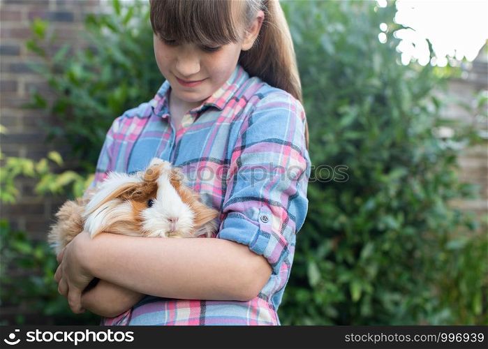 Girl Holding Pet Guinea Pig Outdoors In Garden