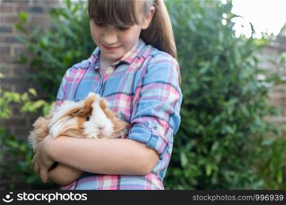 Girl Holding Pet Guinea Pig Outdoors In Garden