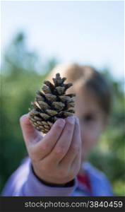 girl holding pine cone in the fall