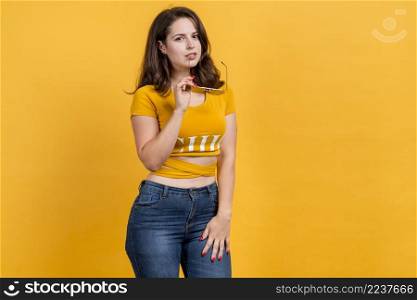 girl holding sunglasses yellow background
