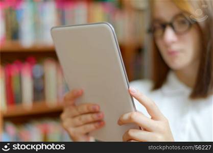 Girl holding tablet. People: young girl, student, making use of tablet computer or e-book reader, in a library or bookstore