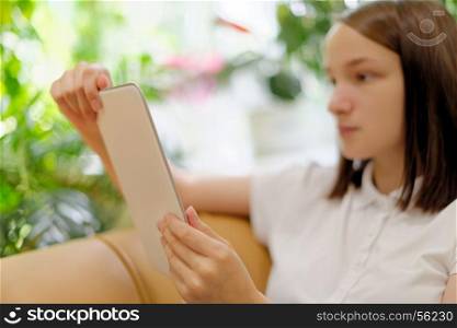 Girl holding tablet. People: young girl, student, making use of tablet computer or e-book reader, in a library or bookstore, selective focus on hands