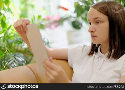 Girl holding tablet. People: young girl, student, making use of tablet computer or e-book reader, in a library or bookstore, selective focus on face
