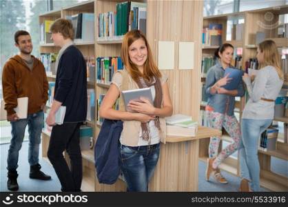 Girl holding tablet with group of students in college library