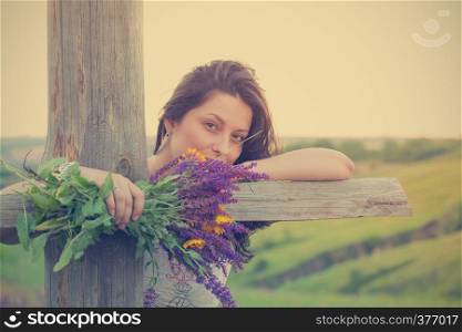 girl holds bouquet of salvia and camomile