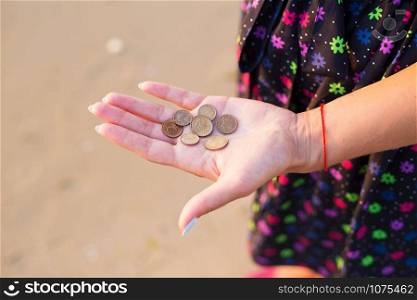 Girl holds coins to throw in the sea. Girl holds coins to throw in sea
