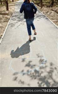 girl hopping in hopscotch on urban alley in sunny day