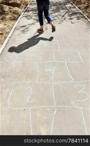 girl hops in hopscotch on urban alley in sunny day
