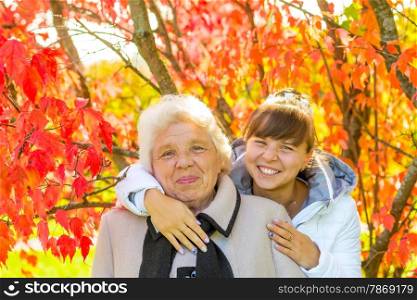 girl hugging her old grandmother in autumn park