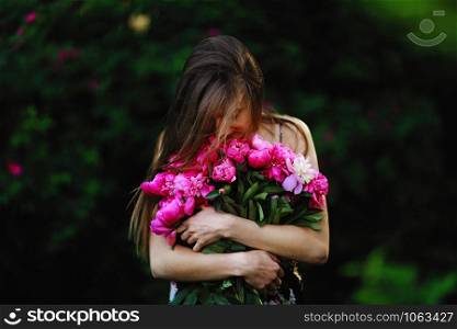 girl hugs a bouquet with flowers. Bouquet of Peony. girl in the field of flowers.. girl in the field of flowers. girl hugs a bouquet with flowers. Bouquet of Peony