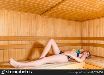 girl in a bathing suit lying on the wooden benches in hot sauna
