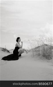 girl in a black long dress in a sandy desert under a blue sky