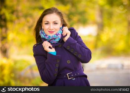 Girl in a dark blue coat against the background of autumn leaves