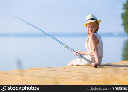 Girl in a dress and a hat with a fishing rod. Girl in a dress and a hat with a fishing rod fishing from the pier