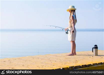 Girl in a dress and a hat with a fishing rod. Girl in a dress and a hat with a fishing rod fishing from the pier