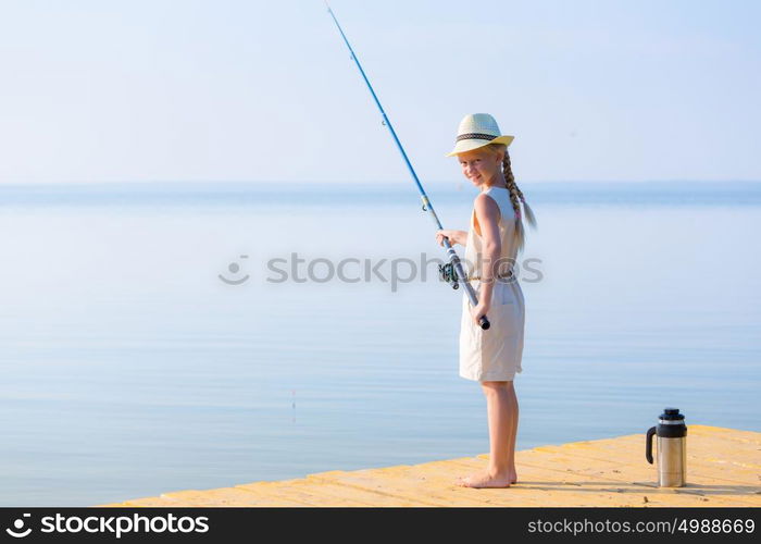 Girl in a dress and a hat with a fishing rod. Girl in a dress and a hat with a fishing rod fishing from the pier