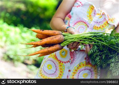 girl in a garden holding a carrot