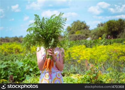 girl in a garden holding a carrot