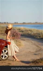 girl in a hat and with a bouquet on the background of the sea. holidays and car travel