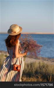 girl in a hat and with a bouquet on the background of the sea