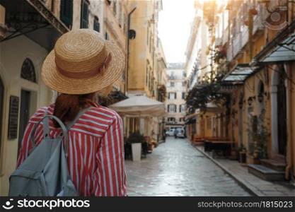 girl in a hat walks on the street of the ancient Greek city. Corfu Island in Greece,