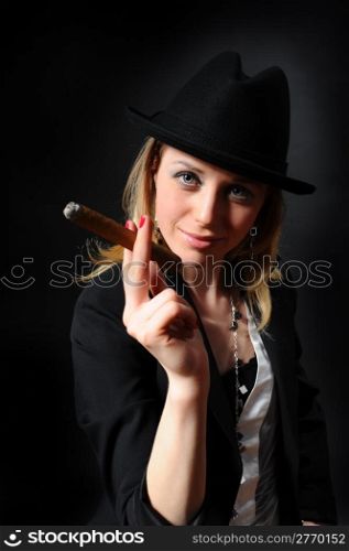 Girl in a hat with a cigar in a hand on a black background