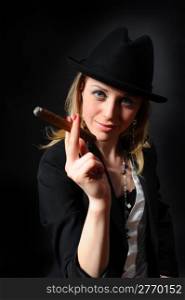 Girl in a hat with a cigar in a hand on a black background