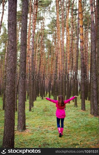girl in a raincoat and rubber boots walking alone in the woods.. girl in a raincoat and rubber boots walking alone in the woods