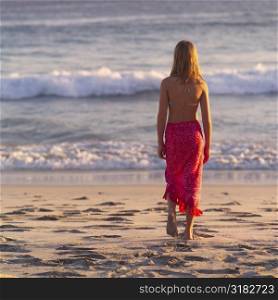 Girl in a sarong walking on the beach