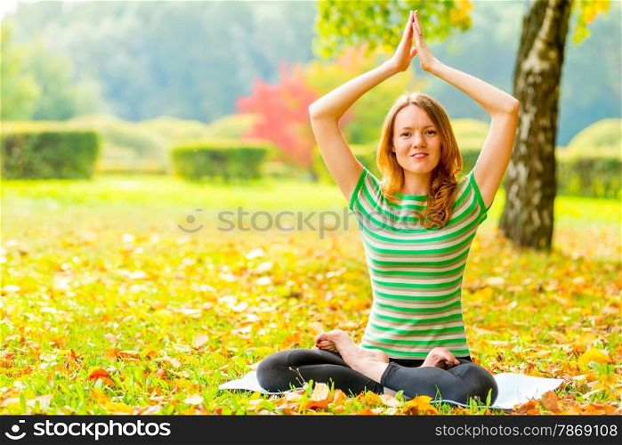 girl in a striped T-shirt in autumn park doing exercises