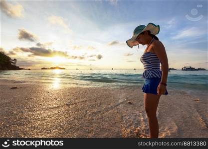 Girl in a swimsuit standing sand and water play with happiness during sunrise on the beach of Honeymoon Bay at Koh Miang, Similan Islands National Park, Phang Nga, Thailand