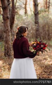 girl in a wedding dress in the autumn forest against the background of wild trees