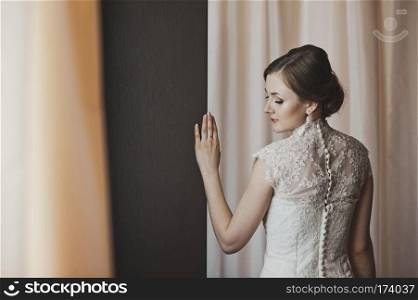 Girl in a wedding dress stands near the curtains.. Portrait of a girl about curtain 3859s
