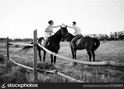 girl in a white sundress and a guy in a white shirt on a walk with brown horses in the village