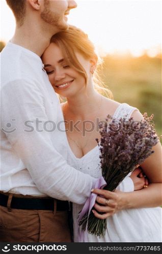 girl in a white sundress and a guy in a white shirt on a walk at sunset with a bouquet in a village outside the city