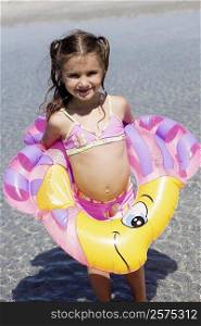 Girl in an inflatable ring standing on the beach